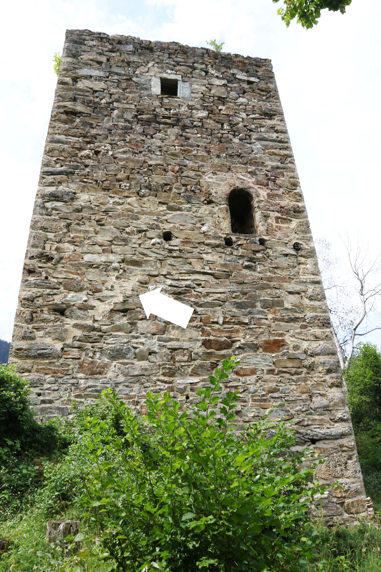 Abb. 5: Die Ostfassade des Turms, mit dem Hocheingang im dritten und dem Sitznischenfenster im vierten Geschoss, im Verputz der Abdruck der Stufen der hölzernen Treppe zum Hocheingang (Pfeil), nach Westen (Y. Alther). 