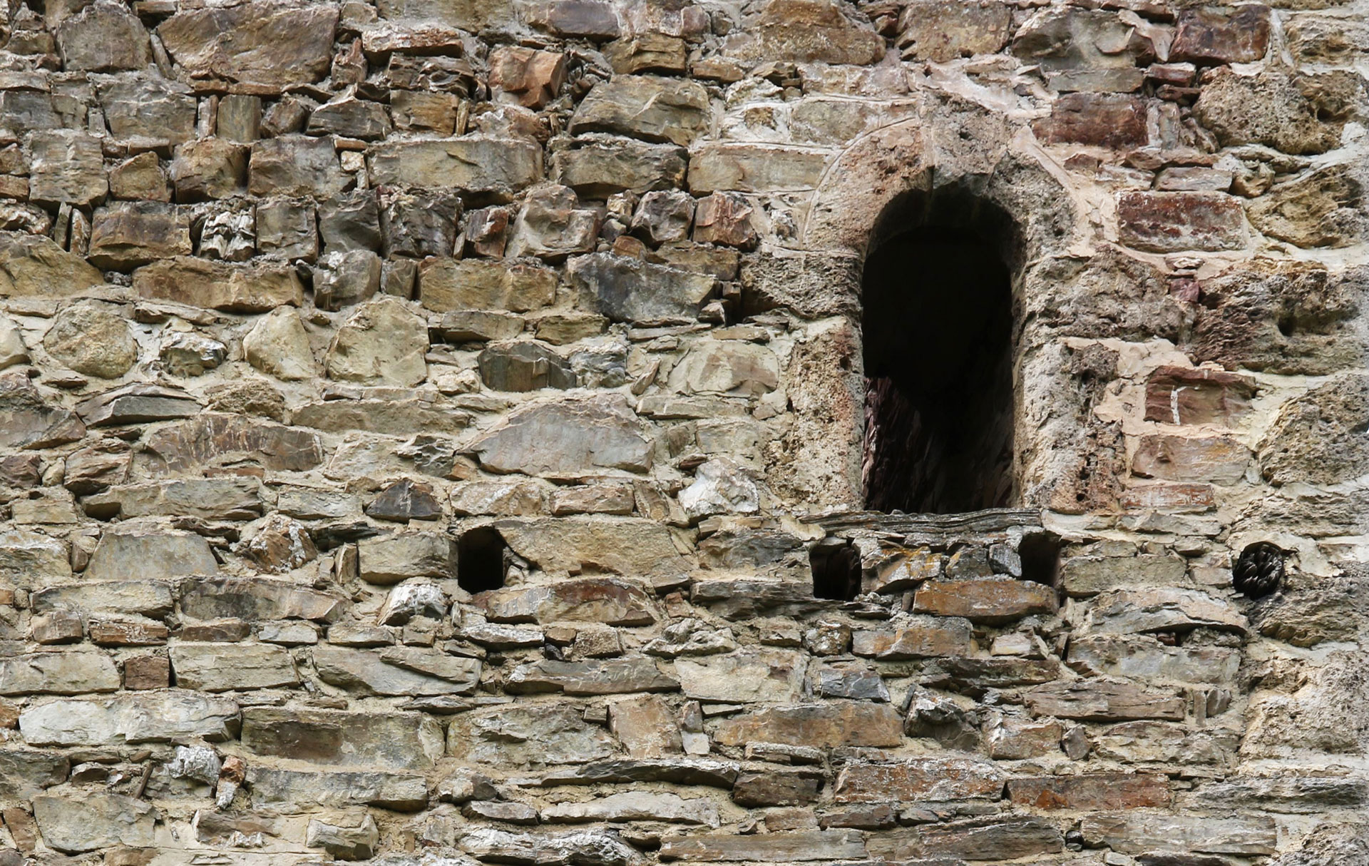 Abb. 6: Detail Ostfassade, Hocheingang. Über dem rundbogigen Eingang zwei Balkenlöcher für das Pultdach. Unterhalb des Hocheingangs, die Balkenlager der hölzernen Laube mit dem Treppenaufgang, nach Westen (Y. Alther).